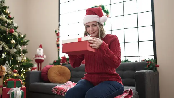 Νεαρή Ξανθιά Γυναίκα Κρατώντας Δώρο Κάθεται Στον Καναπέ Από Χριστουγεννιάτικο — Φωτογραφία Αρχείου