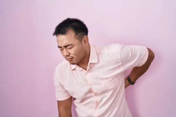 Китайский Молодой Человек Стоит Розовом Фоне Страдает Боли Спине Касаясь — стоковое фото