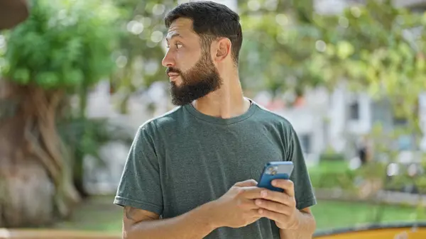 Joven Hombre Hispano Usando Smartphone Con Expresión Seria Parque — Foto de Stock