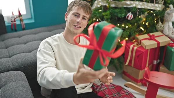 Młody Biały Mężczyzna Dając Boże Narodzenie Prezent Siedzi Podłodze Domu — Zdjęcie stockowe