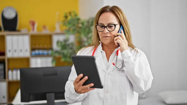Latynoski Lekarz Średnim Wieku Rozmawiający Smartfonie Pomocą Touchpada Klinice — Zdjęcie stockowe