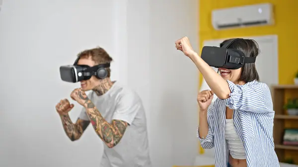 Beautiful couple playing boxing video game using virtual reality glasses at home