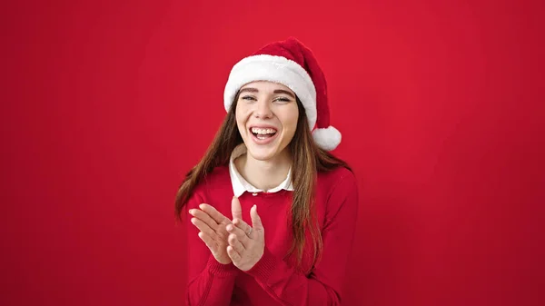 年轻而惊慌的女人戴着圣诞礼帽 在孤独的红色背景上拍手叫好 — 图库照片