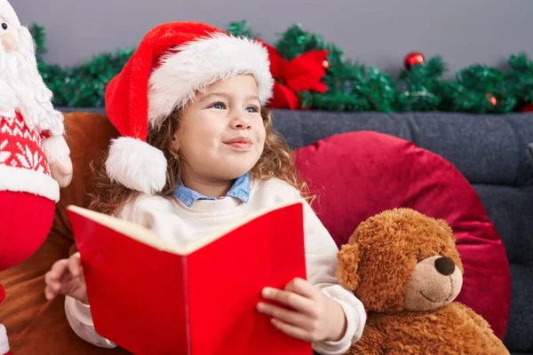可爱的金发碧眼的幼儿坐在沙发上看书 坐在家里的圣诞装饰品旁 — 图库照片