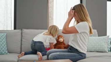 Kafkasyalı anne ve kız, kanepede zıplarken kıkırdayarak birbirlerine bağlanıyorlar, rahatlatıcı evlerinde neşe saçıyorlar.