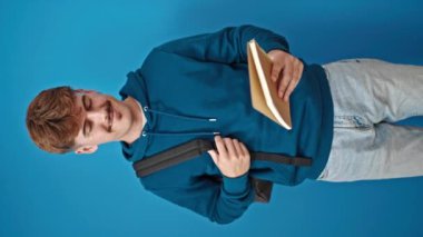 Genç İspanyol öğrenci kitap okuyor ve mavi arka planda kutlama yapıyor.