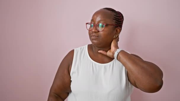 忧心忡忡的非洲裔美国女人 头戴辫子 遭受着严重的宫颈疼痛 不幸地站在孤立的粉红背景墙上 — 图库视频影像
