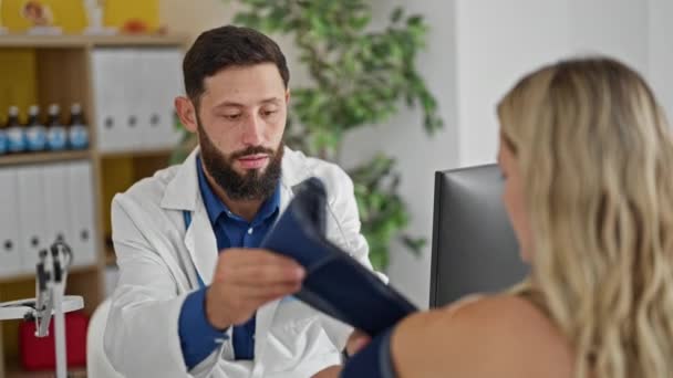 Ung Latinamerikansk Man Läkare Mäter Patientens Puls Med Armtensiometer Kliniken — Stockvideo