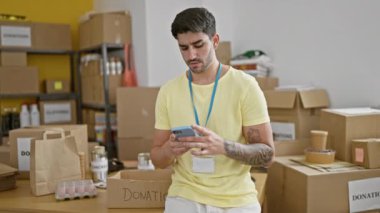 Genç İspanyol gönüllü gönüllü hayır kurumunda akıllı telefon kullanarak gülümsüyor.