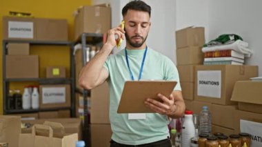 Genç Arap gönüllü yardım merkezinde akıllı telefondan kitap okuyor.