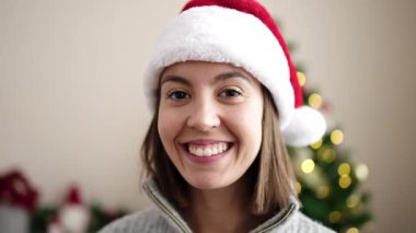 Genç, güzel, İspanyol bir kadın Noel ağacının yanında durmuş evde öpüşüyor.