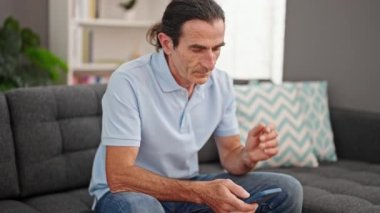 Orta yaşlı bir adam evde rahim ağrısı için akıllı telefon kullanıyor.