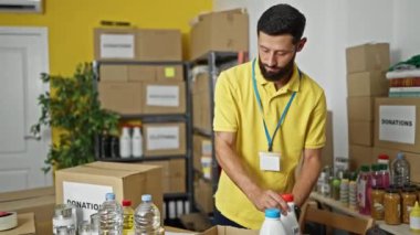 Genç İspanyol gönüllü yardım merkezindeki karton kutuya ürünler koyuyor.