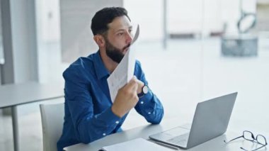 Genç İspanyol iş adamı ofiste el hayranı olarak belgeyi kullanıyor.