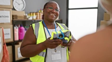Neşeli Afro-Amerikan kadın gönüllü, yerel yardım merkezinde yansıtıcı yelek dağıtıyor. Birleşmiş Milletler 'in hizmetleri sayesinde.
