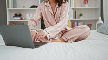 Genç bir kadın yatak odasında online yoga egzersizi yapıyor.