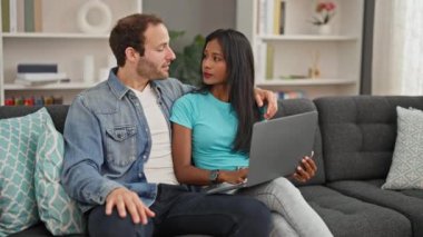 Evdeki kanepede oturup gülümseyen güzel bir çift.