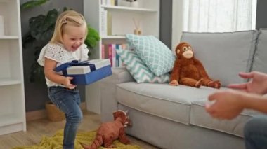 Beyaz anne ve küçük kız evlerinin rahat oturma odasında birbirlerine doğum günü hediyeleriyle sürpriz yapıyorlar. İki kuşak özel bir anı kutluyor..