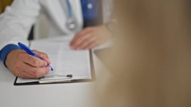 Genç İspanyol doktor klinikteki hastaya tıbbi rapor yazıyor.