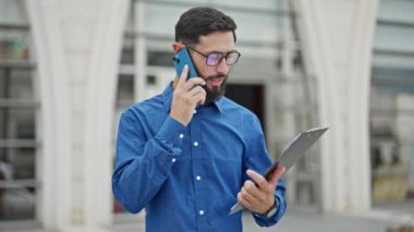 Genç İspanyol iş adamı. Belge okuyor. Sokakta akıllı telefondan konuşuyor.
