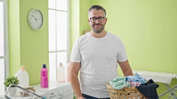 头发灰白的男人自信地站在洗衣房的晾衣绳旁笑着 — 图库视频影像