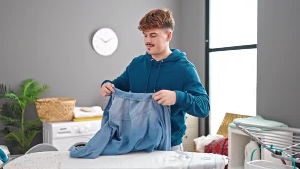Молодий Іспаномовний Чоловік Прасує Одяг Тримаючи Джинсову Сорочку Пральні — стокове відео