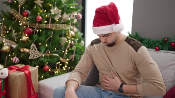 Hombre Árabe Joven Sufriendo Dolor Estómago Sentado Junto Árbol Navidad — Vídeo de stock