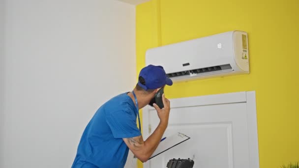 Junger Hispanischer Mann Repariert Klimaanlage Und Spricht Hause Mit Smartphone — Stockvideo