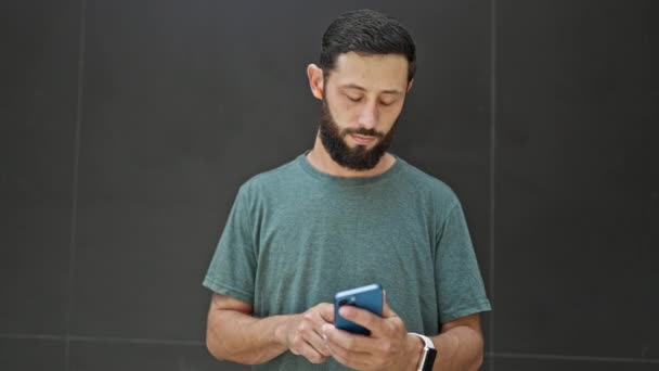 Jonge Spaanse Man Met Behulp Van Oortelefoons Kijken Horloge Smartphone — Stockvideo