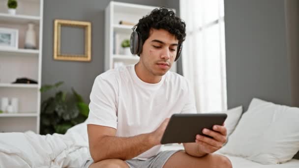 Νεαρός Λατίνος Άντρας Που Χρησιμοποιεί Touchpad Κάθεται Στο Κρεβάτι Φορώντας — Αρχείο Βίντεο