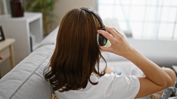 Молодая Женщина Слушает Музыку Сидя Дома Диване — стоковое видео