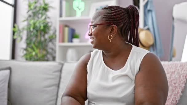 끈이있는 쾌활한 아프리카계 미국인 자신감 집에서 편안하게 편안하게 아늑한 소파에 — 비디오