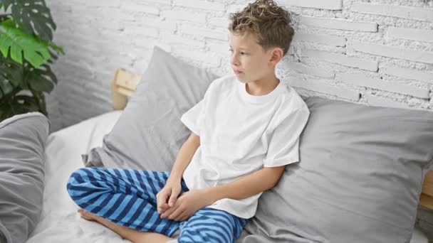 Αξιολάτρευτο Ξανθό Αγόρι Κάθεται Στο Κρεβάτι Σταυρωμένα Χέρια Δείχνοντας Αναστατωμένος — Αρχείο Βίντεο