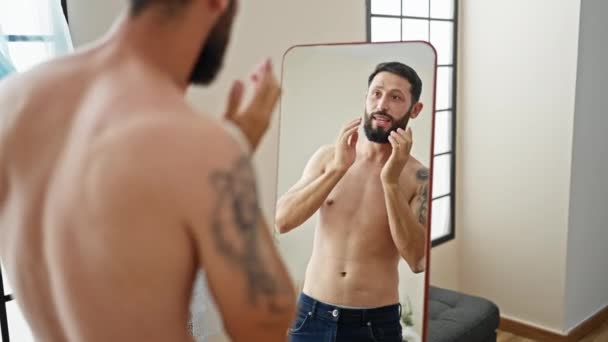 自宅で鏡を見ているひげに触れる若いヒスパニックの男 — ストック動画