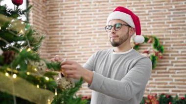 İspanyol adam evde Noel ağacı süslüyor.