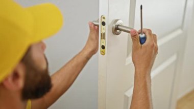 Genç İspanyol adam evde kapı tokmağını tamir ediyor.