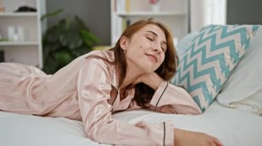 Young woman smiling confident lying on bed at bedroom