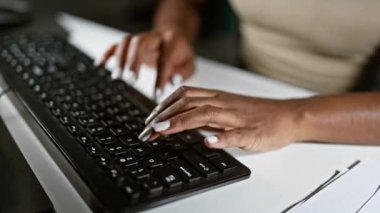 Ofisteki klavyede bilgisayar kullanan Afrikalı Amerikalı kadın.