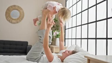 Kendine güvenen beyaz anne ve kız tembel bir sabah geçiriyorlar, gülümsüyorlar ve rahat yatak odalarında birlikte eğleniyorlar.