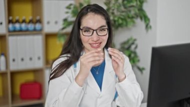 Genç, güzel İspanyol kadın doktor klinikte bilgisayar kullanıyor gözlüğünü çıkarıyor.