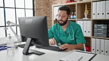 Genç İspanyol doktor klinikteki bilgisayarla video görüşmesi yapıyor.