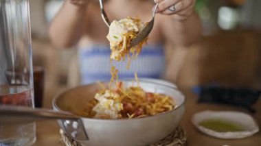 Genç İspanyol kadın restoranda çatal bıçakla yemeği karıştırıyor.