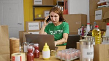 Genç bir kadın yardım merkezinde bilgisayarını ve dokunmatik bilgisayarını kullanarak akıllı telefondan konuşuyor.