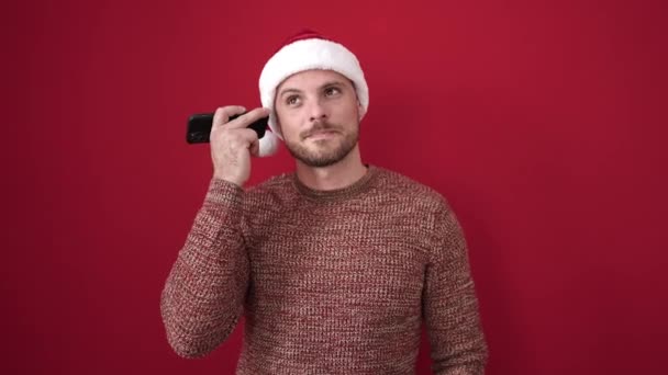 Junger Kaukasischer Mann Hört Sprachnachricht Und Trägt Weihnachtsmütze Über Isoliertem — Stockvideo