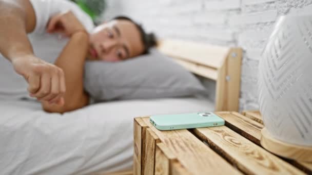 寝室で寝ているスマートフォンで時間を探している若い中国人男性 — ストック動画