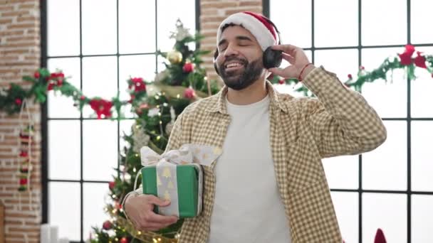 Mladý Hispánec Poslouchá Hudbu Drží Vánoční Dárek Doma — Stock video