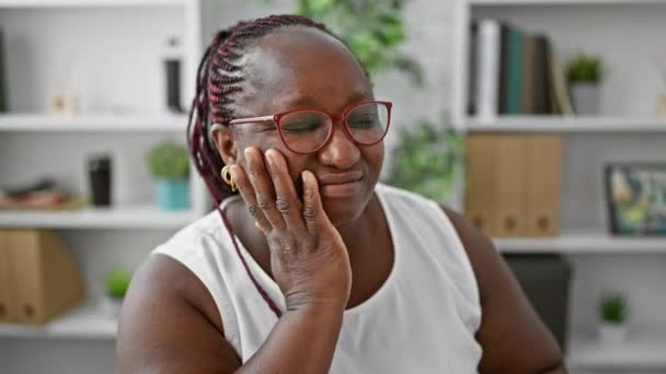 アフリカ系アメリカ人ビジネス女性労働者は オフィスでラップトップに取り組んでいる間に歯痛に苦しみ 深刻な顔を通して彼女の痛みを示しています — ストック動画