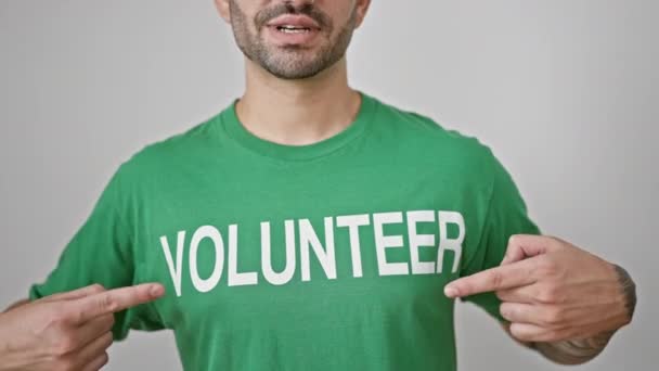 年轻的惊慌失措的男人指着志愿者的制服 对着孤立的白色背景微笑 — 图库视频影像