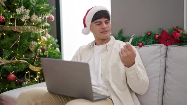 若いですヒスパニック男ショッピングとともにラップトップとクレジットカードお祝いクリスマス ホーム — ストック動画