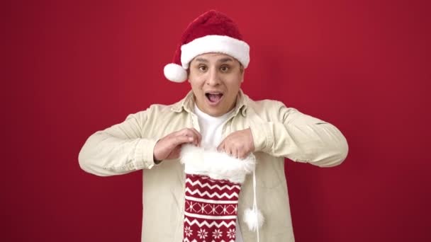 Jovem Hispânico Vestindo Chapéu Natal Olhando Para Dentro Meia Sobre — Vídeo de Stock